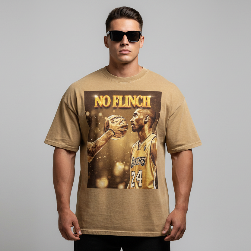 Man wearing a tan kobe bryant t-shirt with a graphic of a basketball player and 'NO FLINCH' text on a gray background